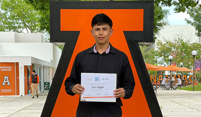 Estudiante ganador del concurso junto al logo de la Universidad Anáhuac de Cancún de México.