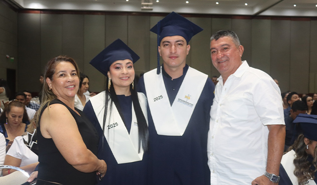 Dos graduandos posan en su ceremonia de grados junto con sus familiares 