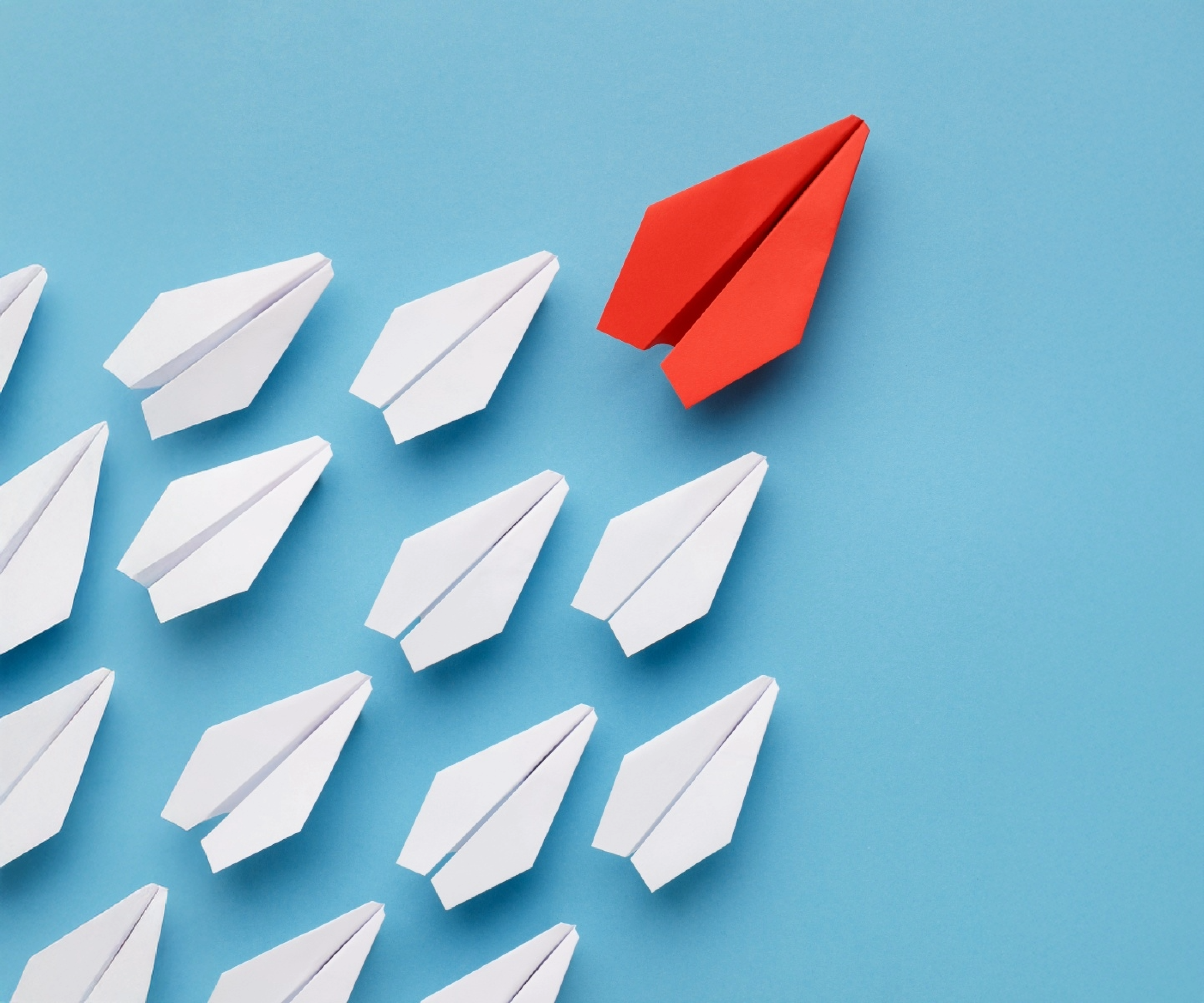 Aviones de papel liderados por un avión de papel mas grande de color rojo