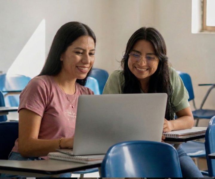dos estudiantes mujeres junto a un portátil UNIMINUTO feria de posgrados