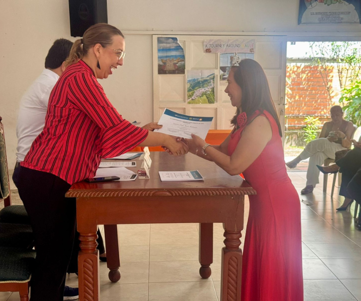 Rectora de UNIMINUTO Tolima–Huila entregando microcredencial en inglés a docente durante acto de certificación en Ibagué, como parte de la estrategia de fortalecimiento del bilingüismo educativo.