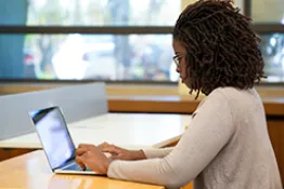 Mujer sentada escribiendo en el computador