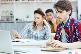 un hombre utilizando un computador y una mujer con el celular en la mano 