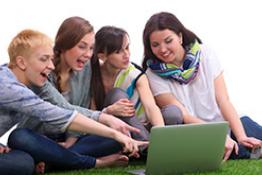 Grupo de mujeres frente a un computador sentadas en el pasto