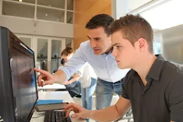 Estudiante y profesor trabajando en computador