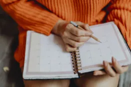 Mujer sentada escribiendo sobre agenda