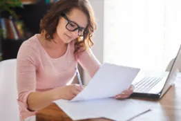 Mujer sentada en escritorio con computador, llenando formato