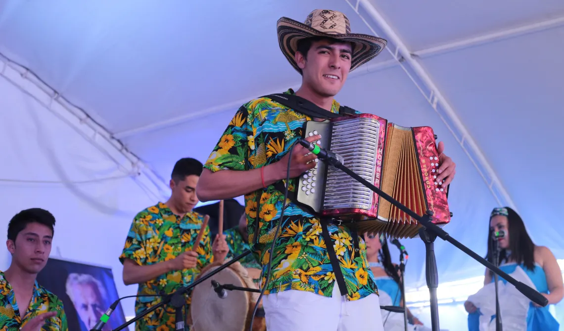 Joven con sombrero vueltiao y camisa colorida, tocando el acordeón.