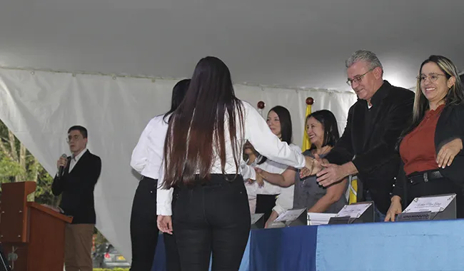 Estudiante recibiendo su certificado de beca UNIMINUTO