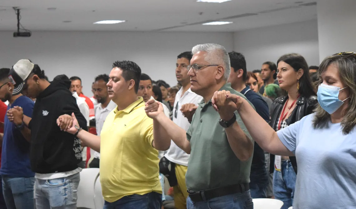 Estudiantes y colaboradores orando, tomados de las manos