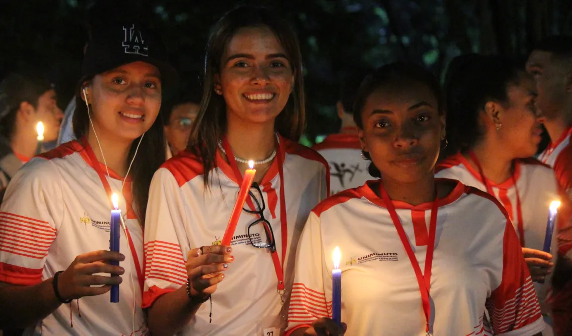 Tres estudiantes alegres con una vela en sus manos