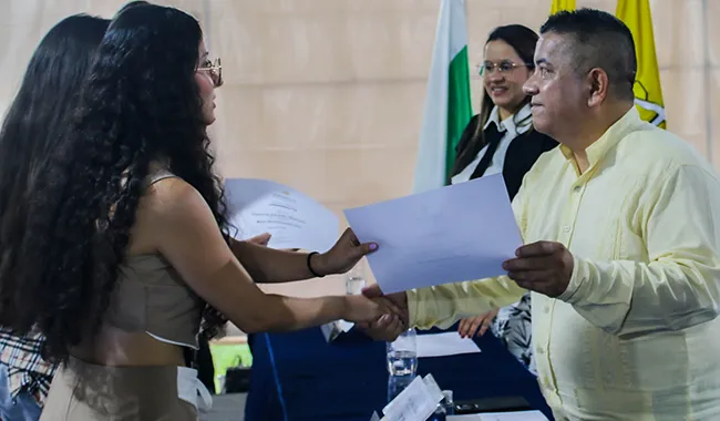 Rector de UNIMINUTO entregado certificado de beca a estudiante beneficiada 