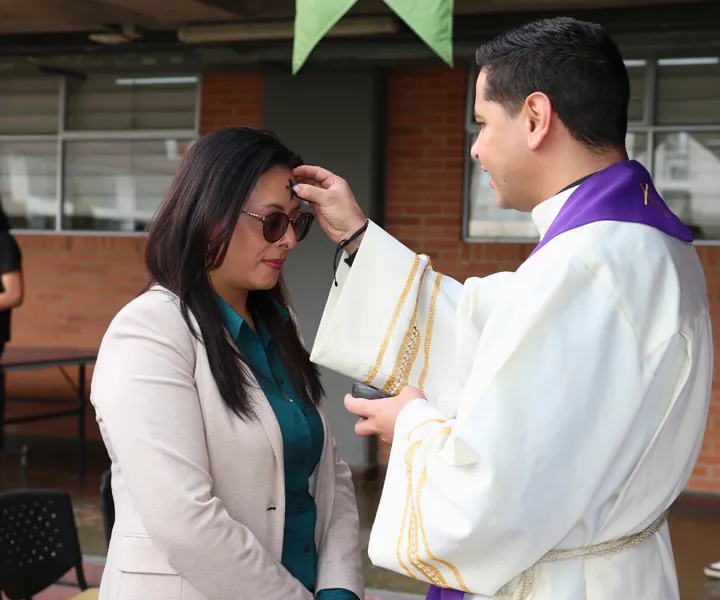 padre imponiendo la ceniza a una mujer