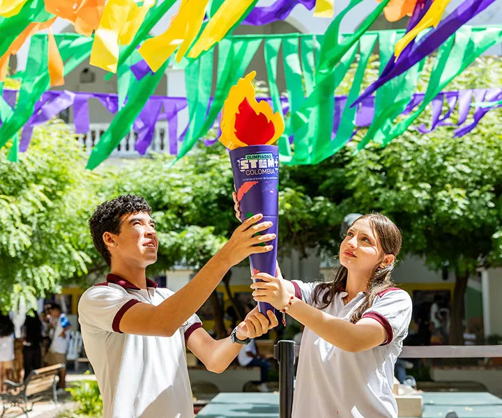 Dos estudiantes sostienen antorcha símbolo de inicio de las olimpiadas STEM 2025