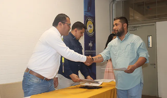 Dos hombres estrechan la mano mientras uno recibe su certificado durante la ceremonia del curso de drones.