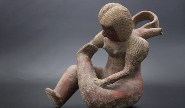 Representación de Mercaderes prehispánicos, una mujer sentada sobre el suelo