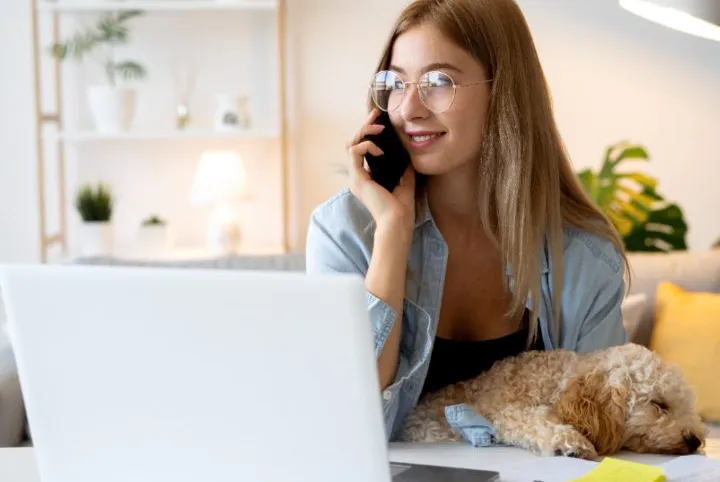 mujer hablando por celular acompañada de su mascota