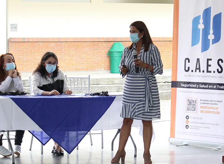 En la plazoleta del campus en Pereira, en una mesa de mantel blanco, los asistentes atienden a la presentación de los servicios del CAES en Pereira