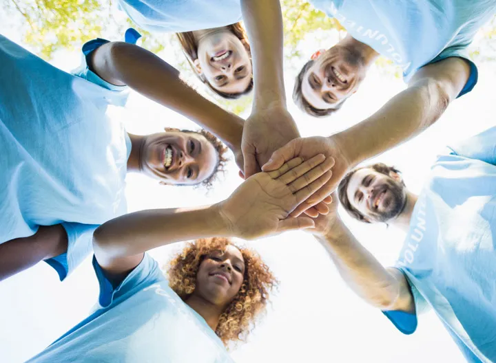 Grupo de personas de camiseta azul uniendo las manos en el centro