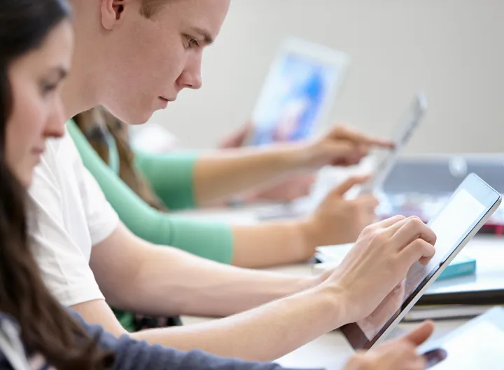 Jóvenes en clase con dispositivos móviles