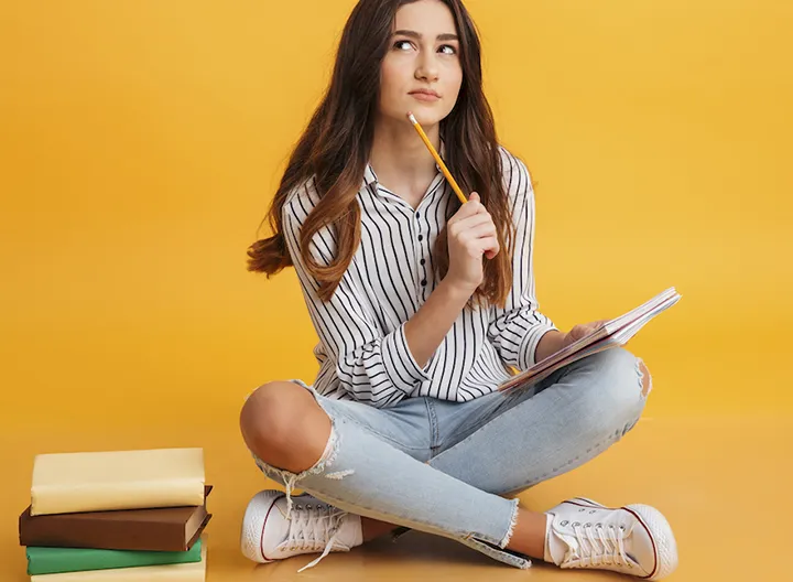 Chica con libros pensando qué escribir