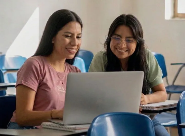 dos estudiantes mujeres junto a un portátil UNIMINUTO feria de posgrados