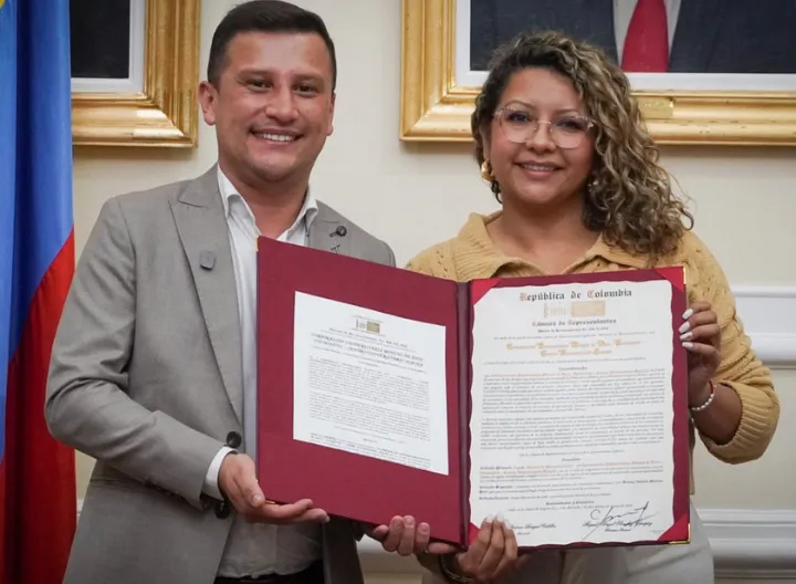 El doctor Víctor Hugo Londoño Aguirre, rector de la Sede UNIMINUTO Cundinamarca-Boyacá, y la Dra. Francy Natalia Moreno Rincón, representante a la Cámara por Cundinamarca, posan junto a la Moción de Reconocimiento otorgada por la Cámara de Representantes a UNIMINUTO Centro Universitario Soacha, en el marco de sus 25 años de compromiso con la educación superior, la transformación social y el desarrollo de la región. 25 años  Transformación social Moción de reconocimiento Historia