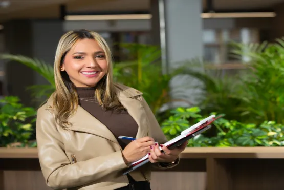 Estudiante sonriente sosteniendo planilla en la mano