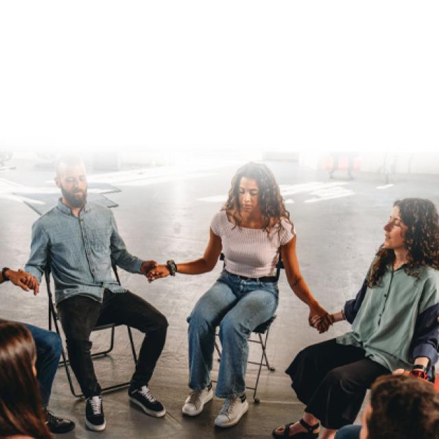 Personas en circulo sentadas tomadas de la mano