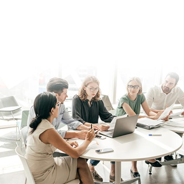 Equipo de trabajo dialogando en mesa con computador