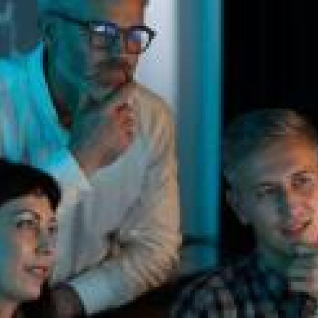 Tres personas mirando pantala digital