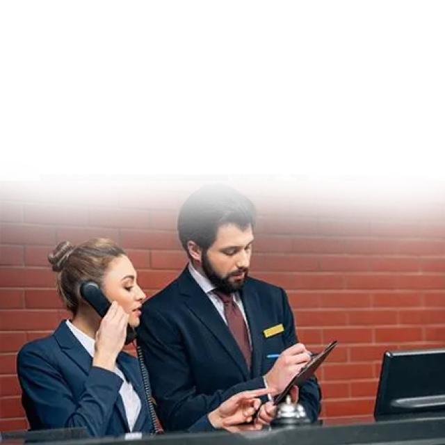 Dos personas en recepción de hotel revisando información