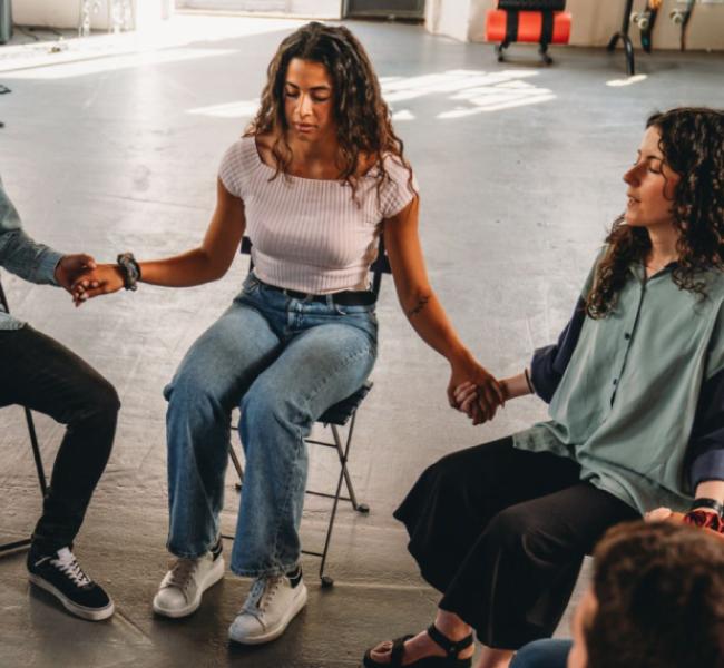 Personas en circulo sentadas tomadas de la mano