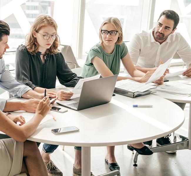 Equipo de trabajo dialogando en mesa con computador