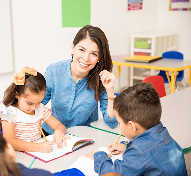 Profesora en mesa de trabajo con niños