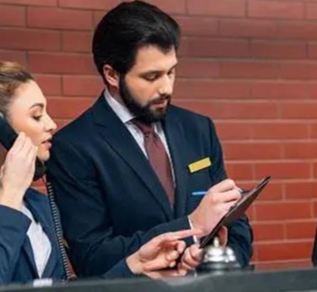 Dos personas en recepción de hotel revisando información